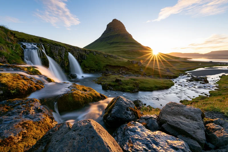 Kirkjufell mountain rising behind cascading waterfall in icelandic landscape at sunrise