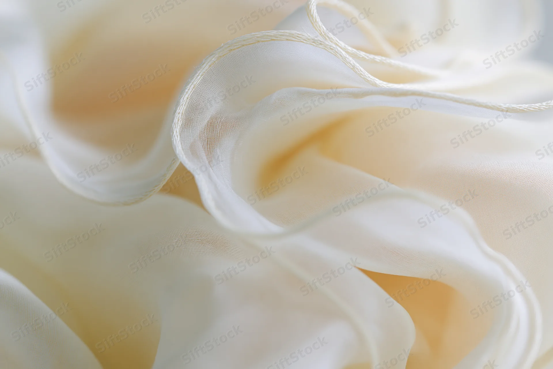 Layers of sheer ivory organza fabric bunched and folded into soft undulations