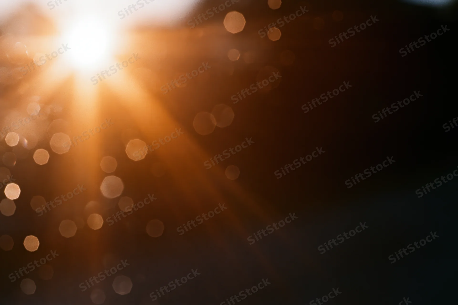 Bright sunburst with lens flare and bokeh lights in abstract outdoor background
