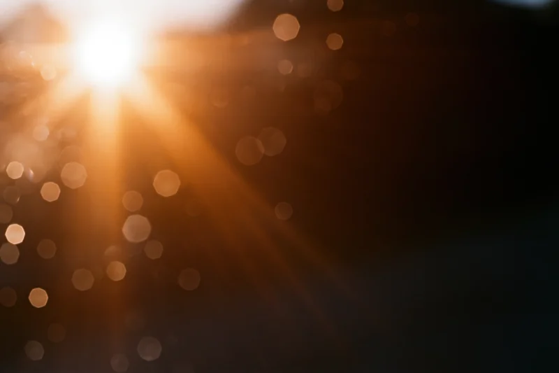 Bright sunburst with lens flare and bokeh lights in abstract outdoor background