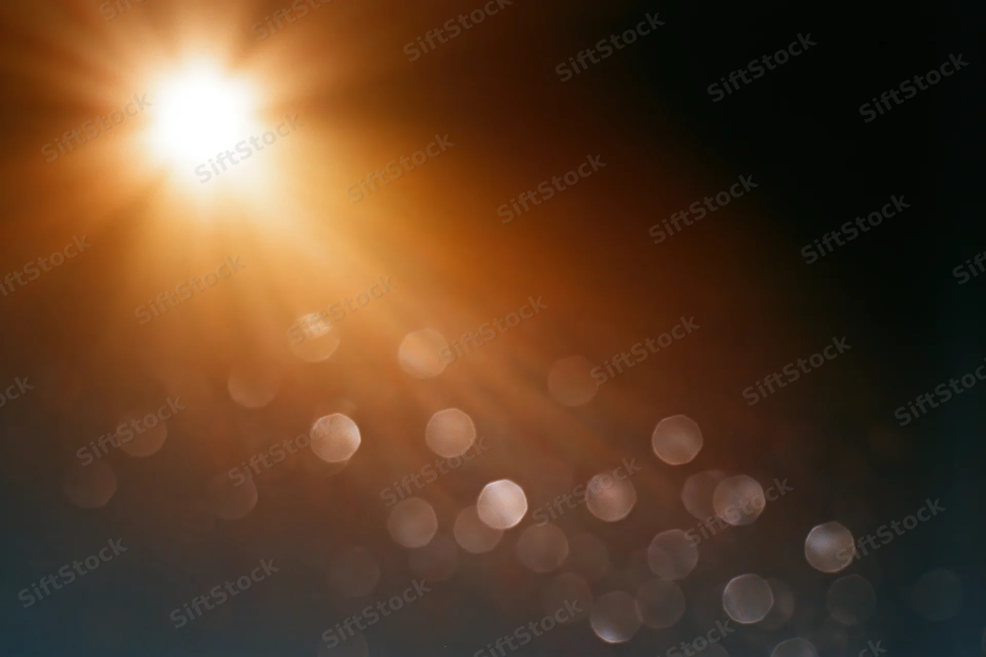 Bright sunburst with lens flare and bokeh lights on dark background