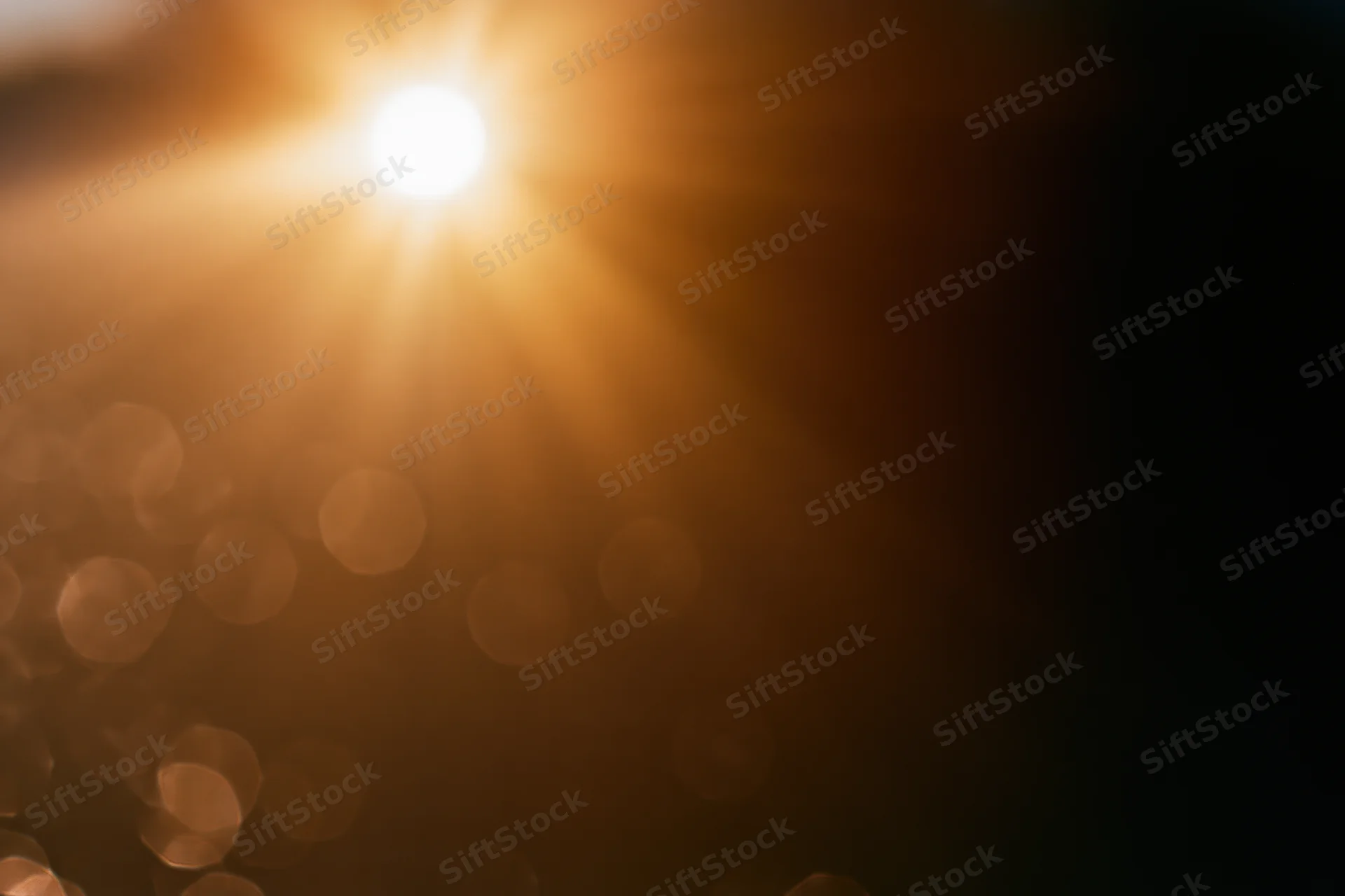 Bright sunburst light source with lens flare and bokeh effect in abstract background