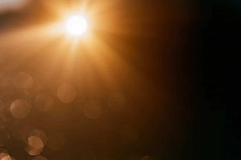 Bright sunburst light source with lens flare and bokeh effect in abstract background