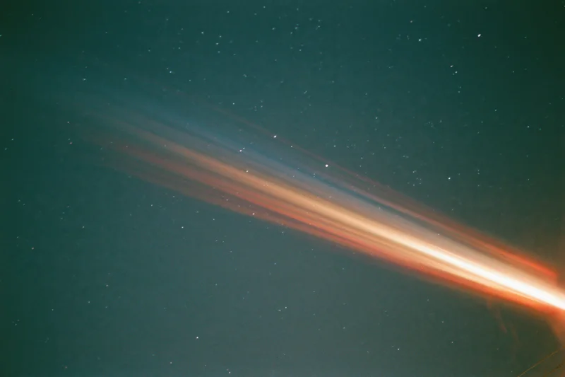 Lens flare and light leak streak across dark night sky with scattered stars