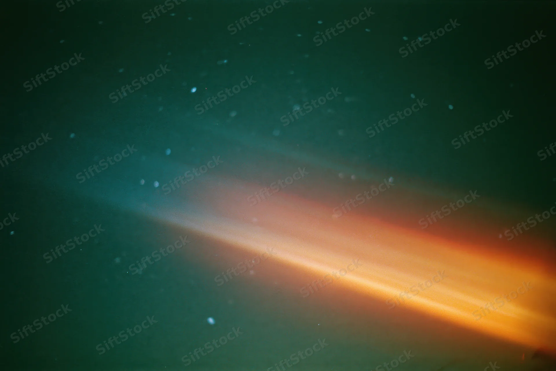 Lens flare and light leak streak across dark night sky with scattered stars