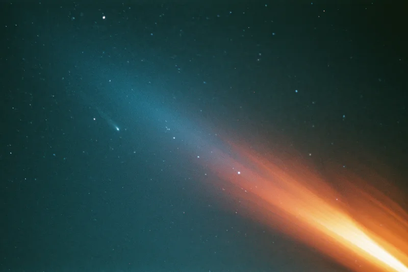 Comet with glowing tail and lens flare across dark starry night sky