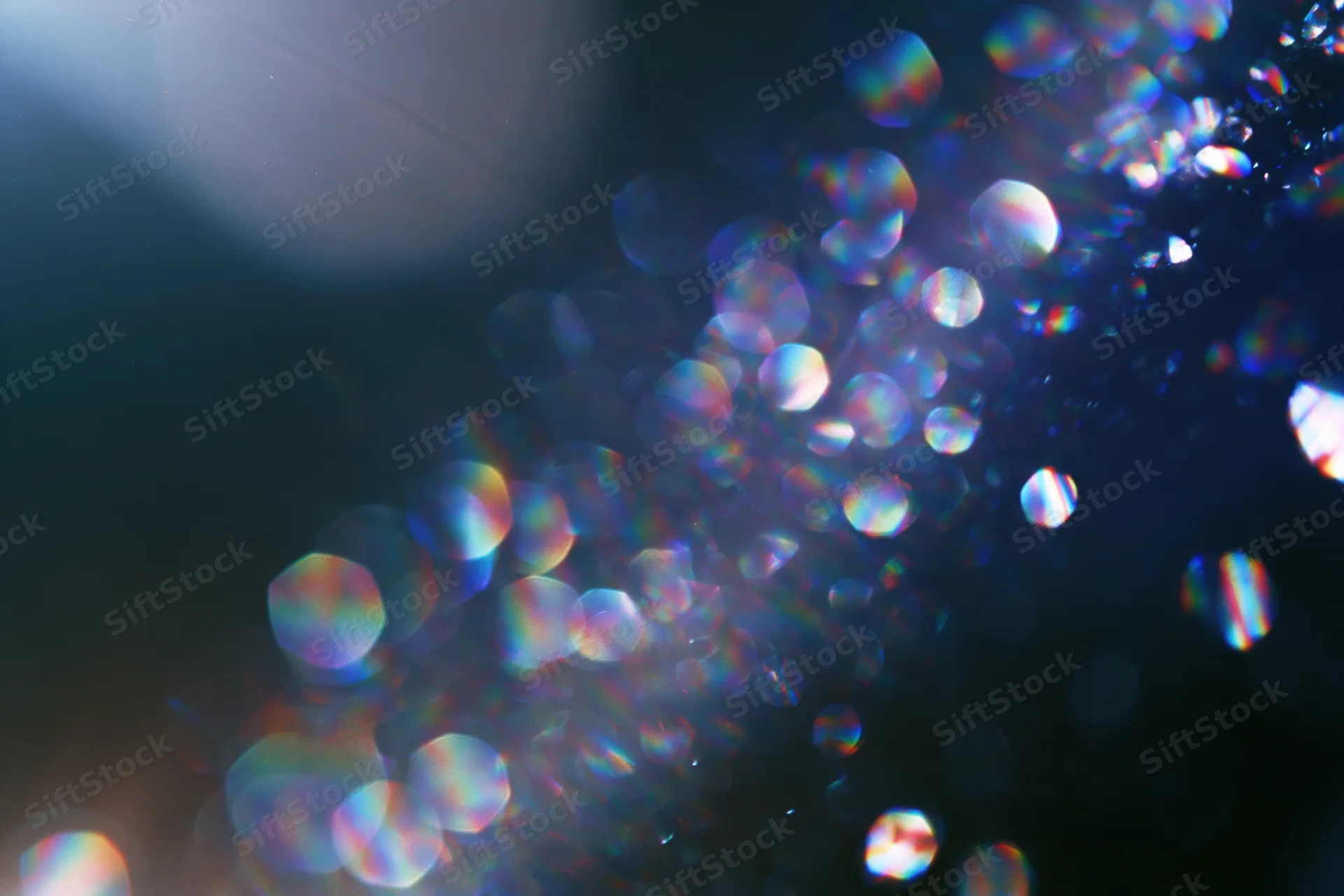 Abstract bokeh lights with rainbow iridescence on dark background