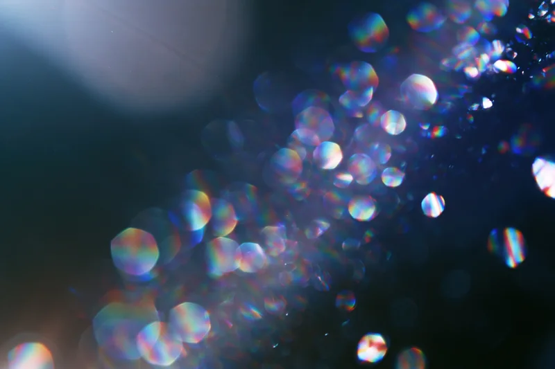 Abstract bokeh lights with rainbow iridescence on dark background