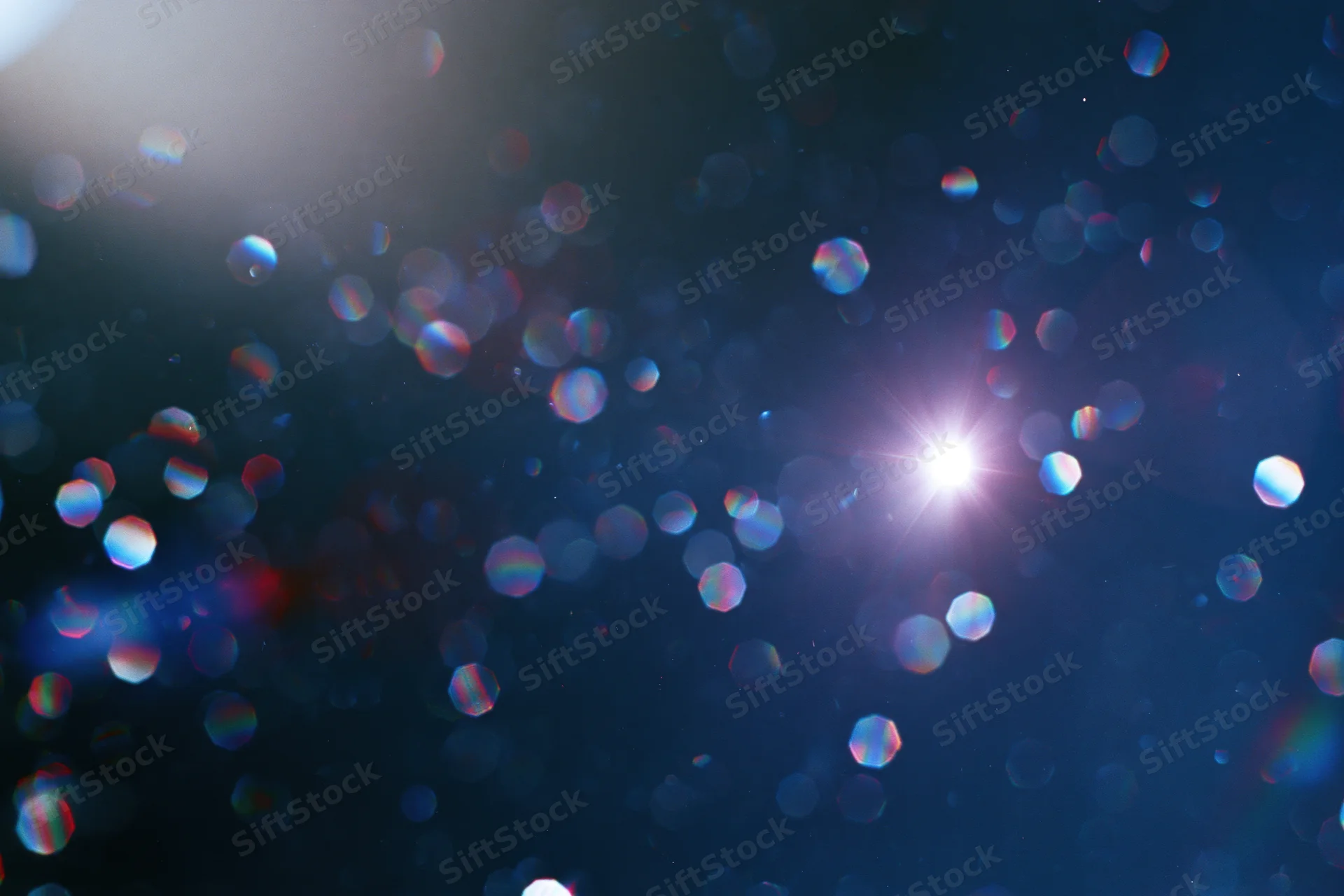 Lens flare and light leak effect on dark abstract background with bokeh highlights and rainbow reflections