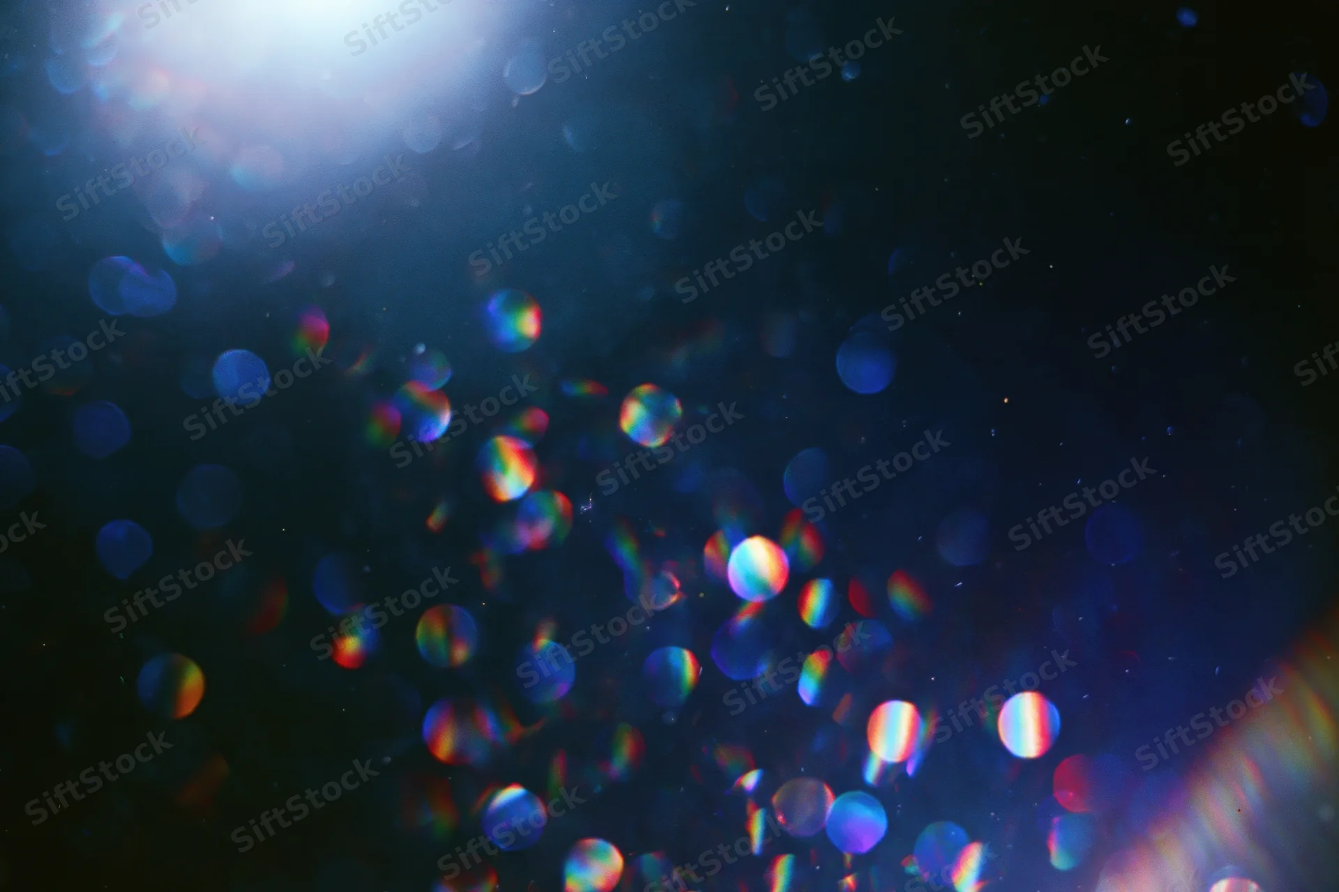 Abstract bokeh lights with lens flare and light leak on dark background
