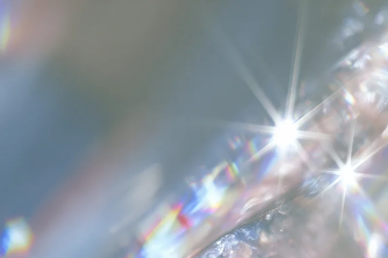 Light refracting through a crystal surface creating starburst and rainbow patterns