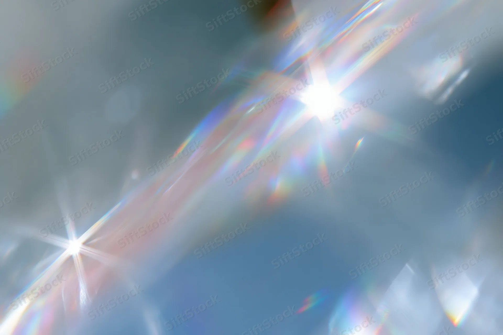 Light refracting through a crystal surface creating a rainbow spectrum against a soft blue background