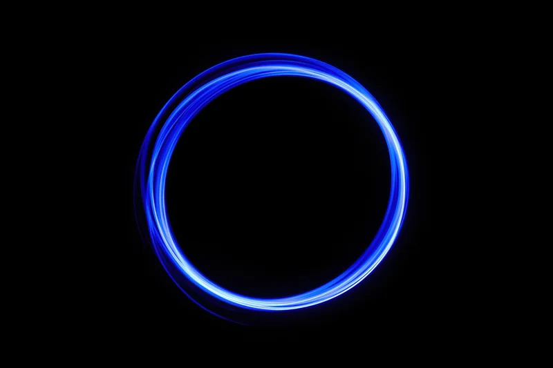 Glowing blue circular light trail in dark background from long-exposure light painting photography