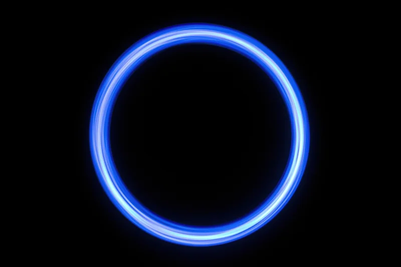 Glowing blue circular light trail against black background from long-exposure light painting photography