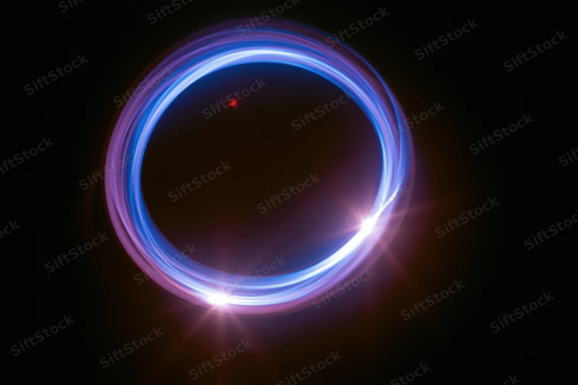 Glowing circular light trail in dark space with blue and purple hues and starburst flares