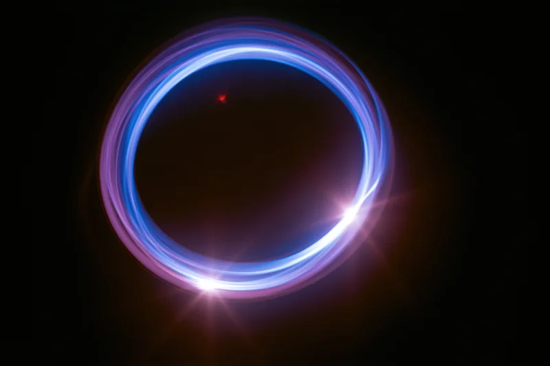 Glowing circular light trail in dark space with blue and purple hues and starburst flares