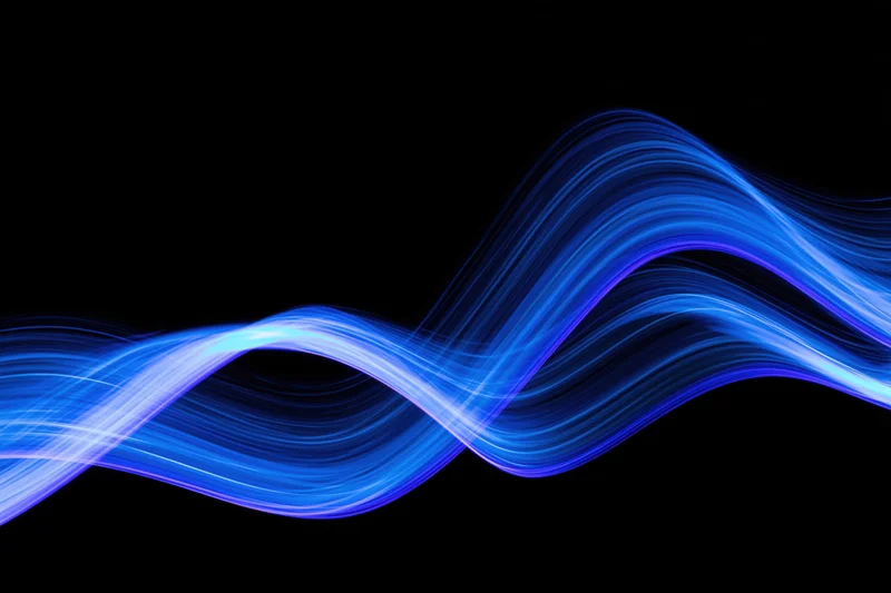 Flowing blue light waves captured in long-exposure light painting photography against black background