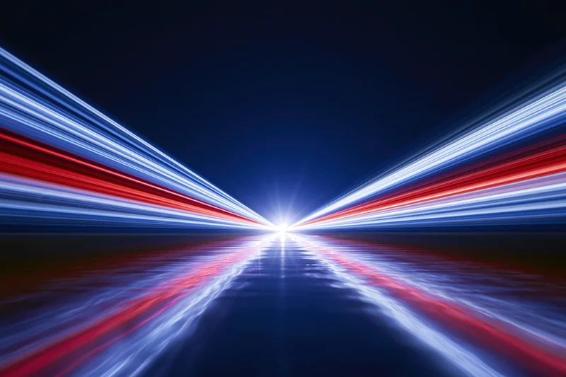 Light trails converging at a vanishing point on a dark road at night