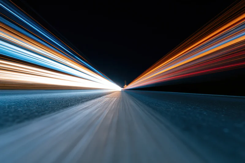 Long-exposure night highway with light streaks from moving vehicles viewed from low road level