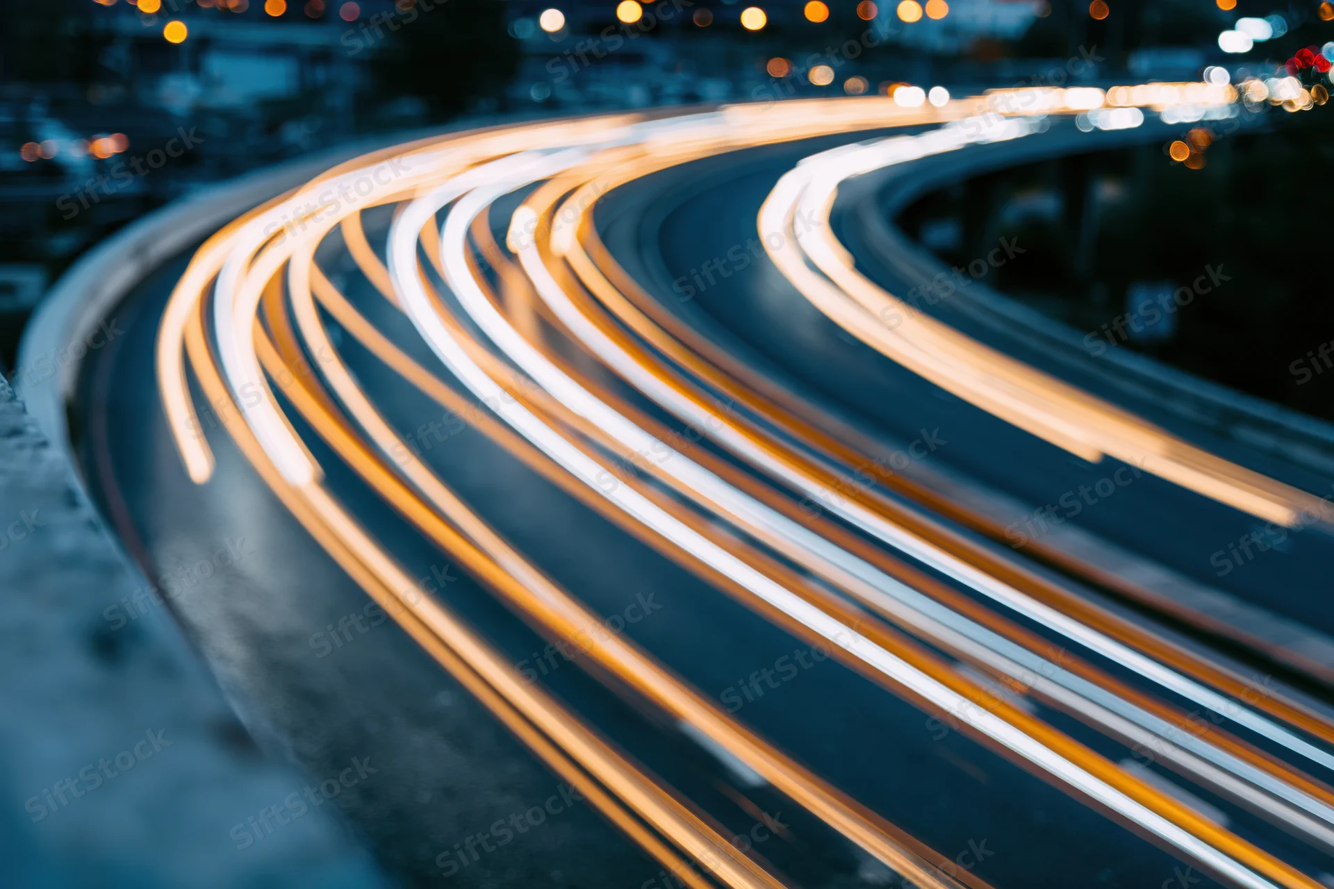 Long-exposure night view of curved urban highway with light trails from moving vehicles