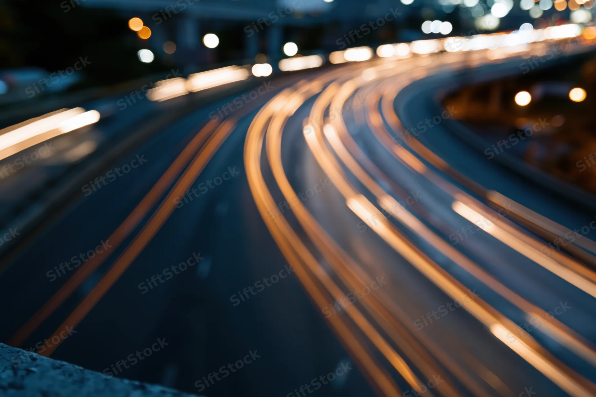 Curved urban highway at night with light trails from moving vehicles