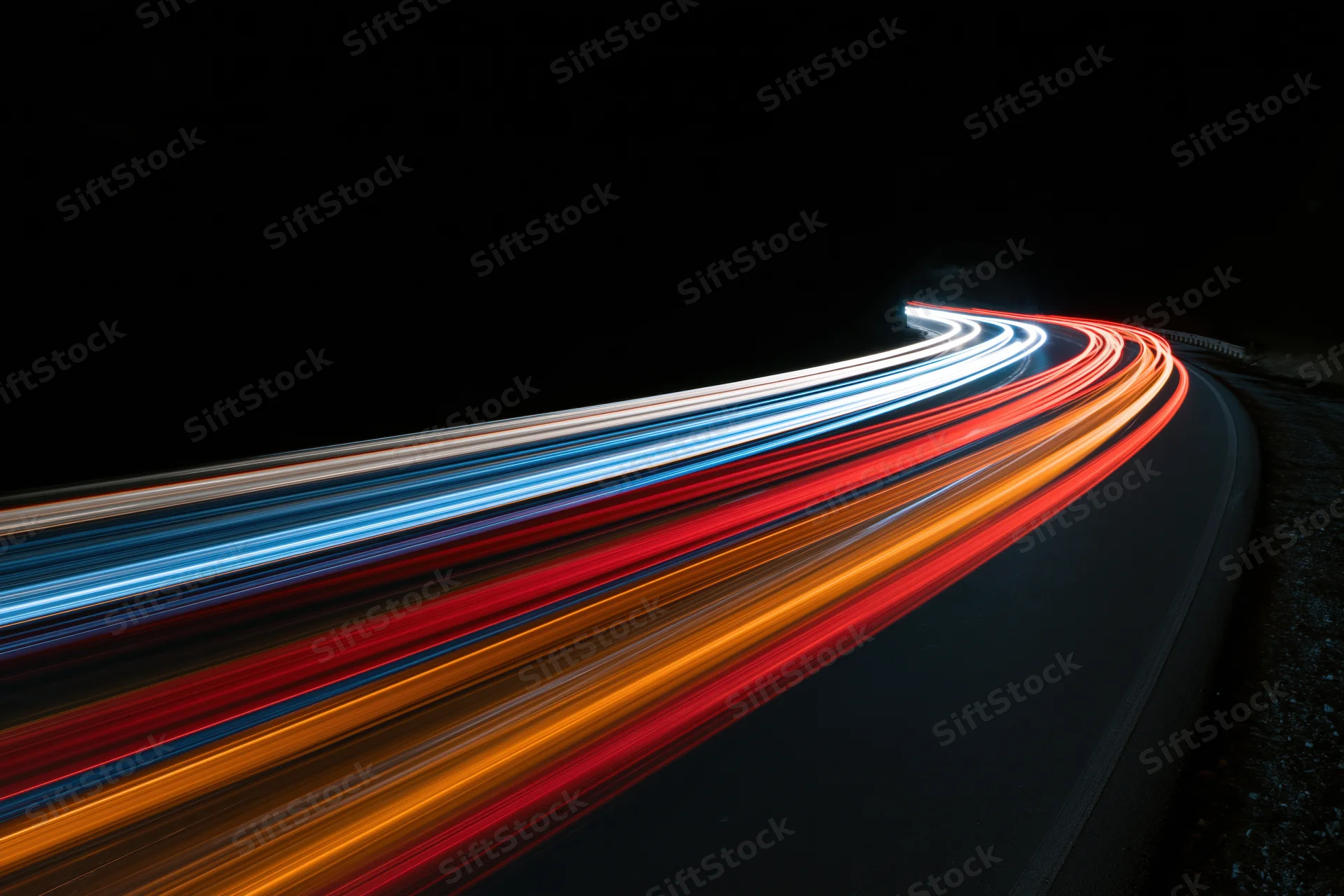 Long-exposure night view of curving highway with streaking vehicle lights