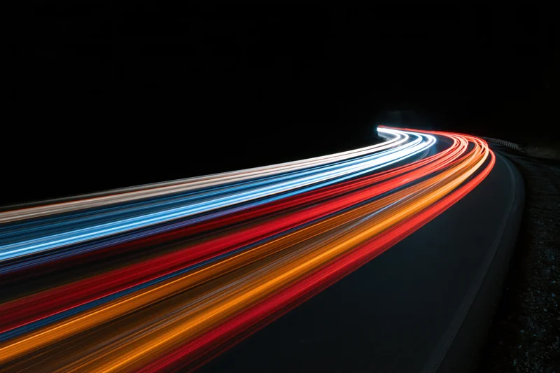 Long-exposure night view of curving highway with streaking vehicle lights