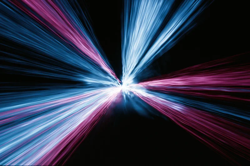 Streaks of blue and pink light radiating from a central point in a dark urban night scene