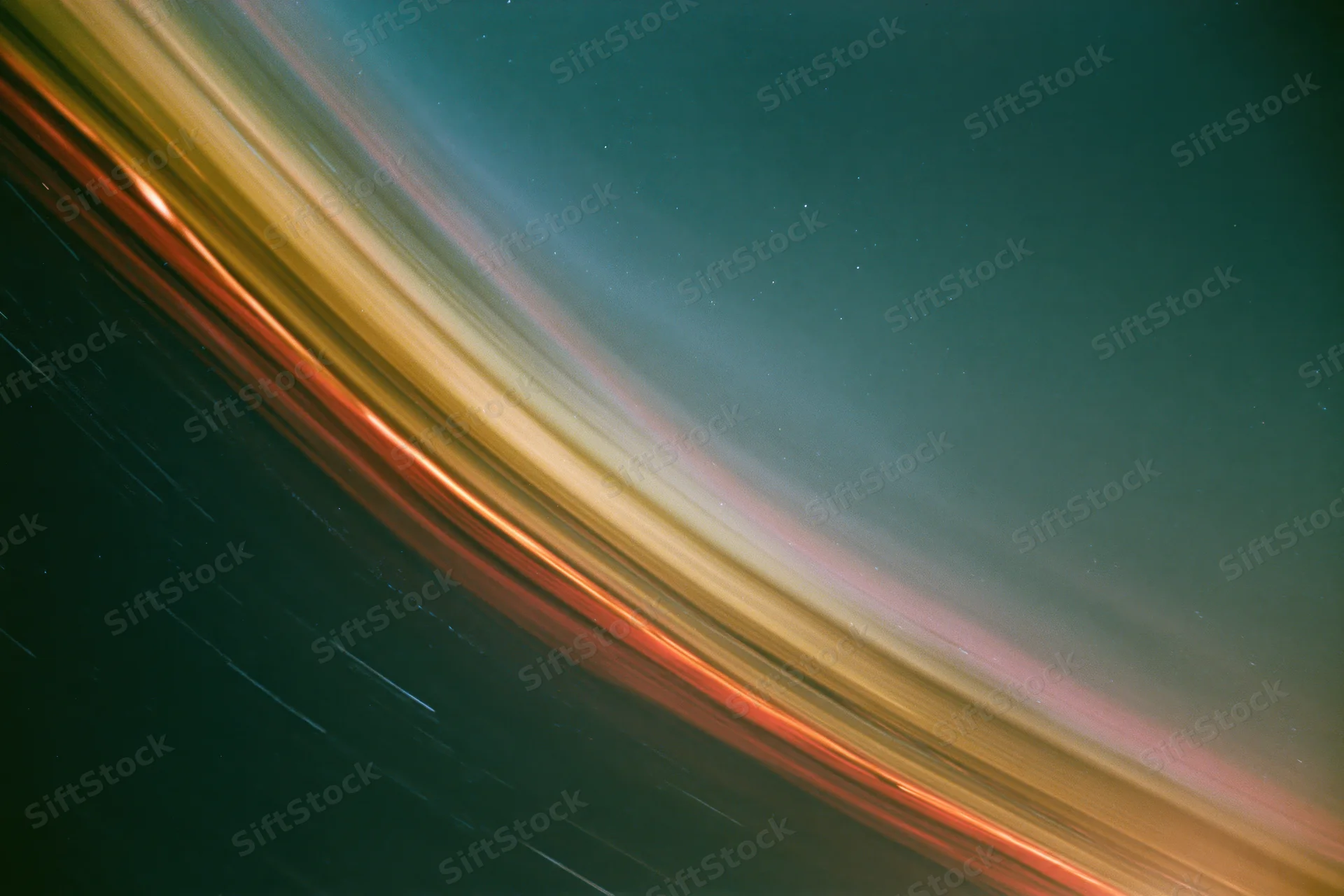 Long-exposure night sky with diagonal star streaks across dark teal and warm-toned gradients