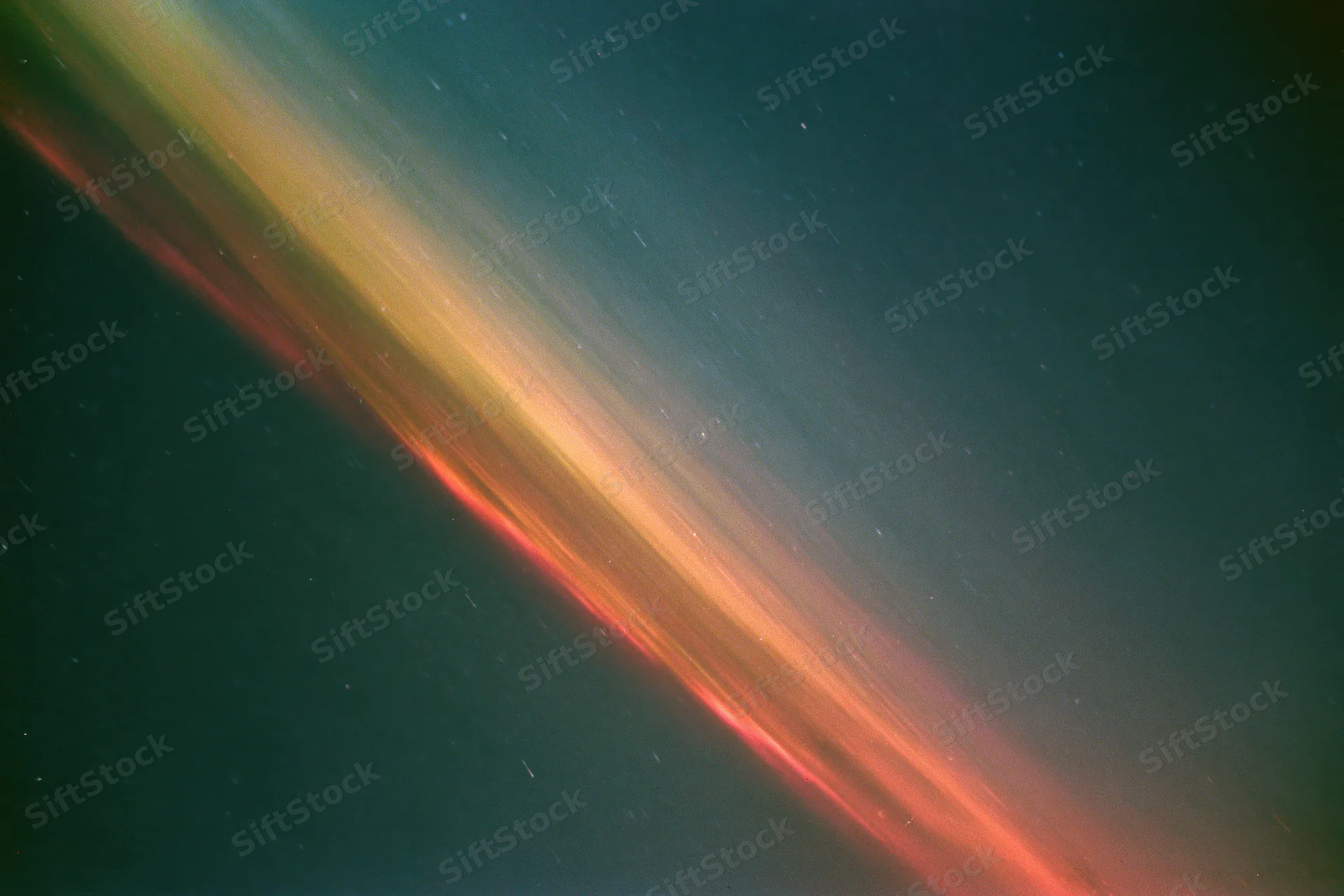 Long-exposure night sky with diagonal light streaks and scattered stars