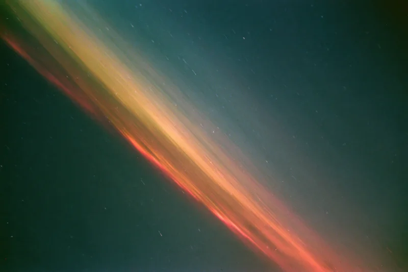 Long-exposure night sky with diagonal light streaks and scattered stars