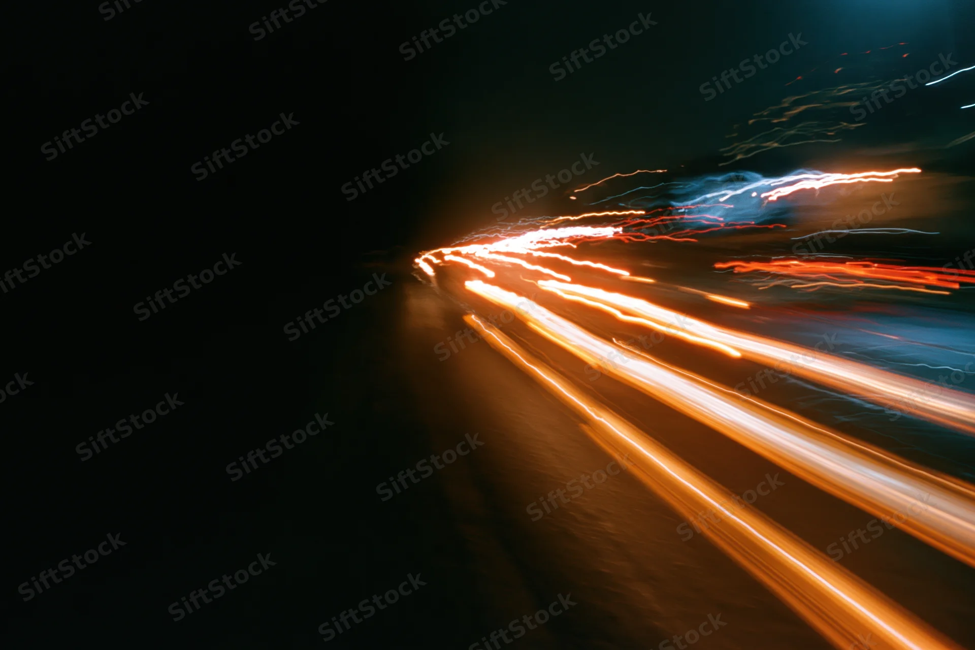 Streaks of vehicle lights moving along a dark city street at night