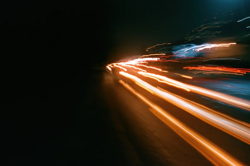 Streaks of vehicle lights moving along a dark city street at night