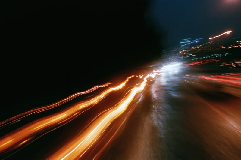 Blurred light trails from moving vehicles on a wet city street at night