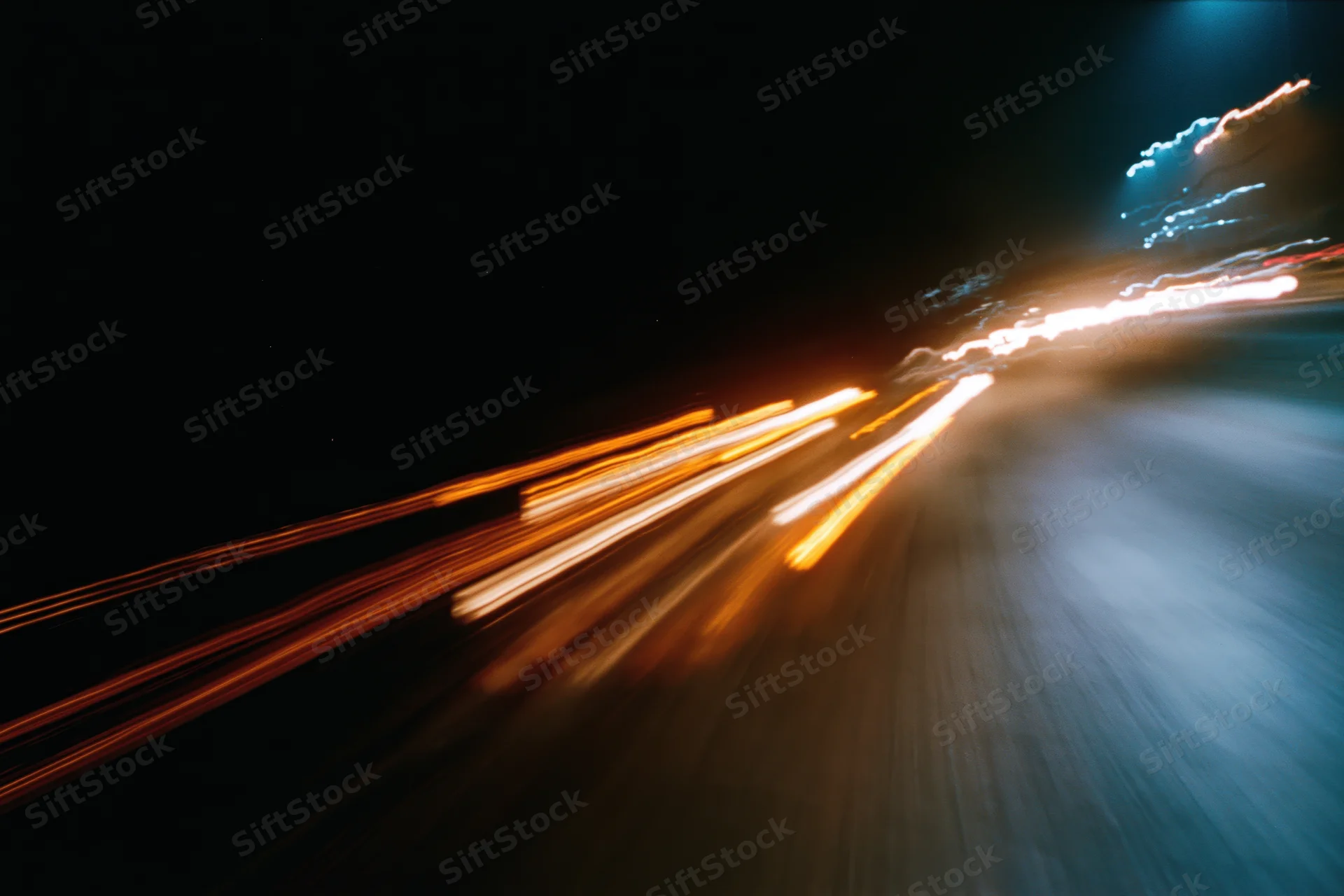 Blurred light trails from moving vehicles on a dark city street at night