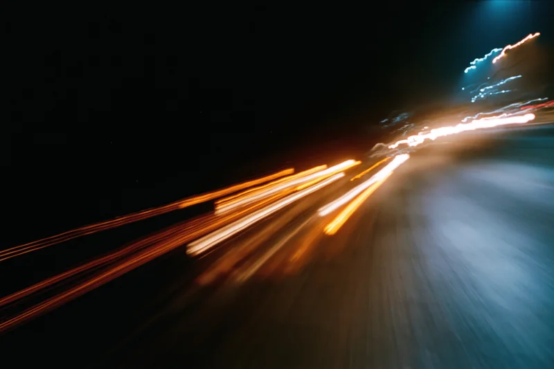 Blurred light trails from moving vehicles on a dark city street at night