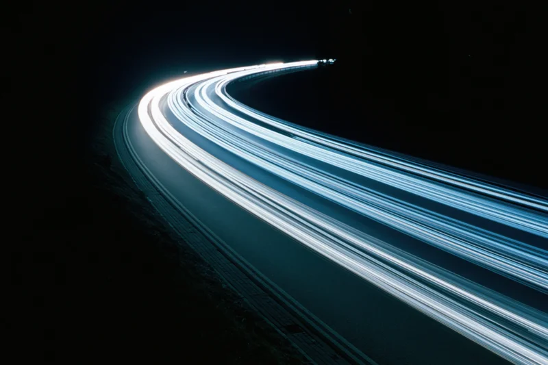 Curved highway at night with light trails from moving vehicles