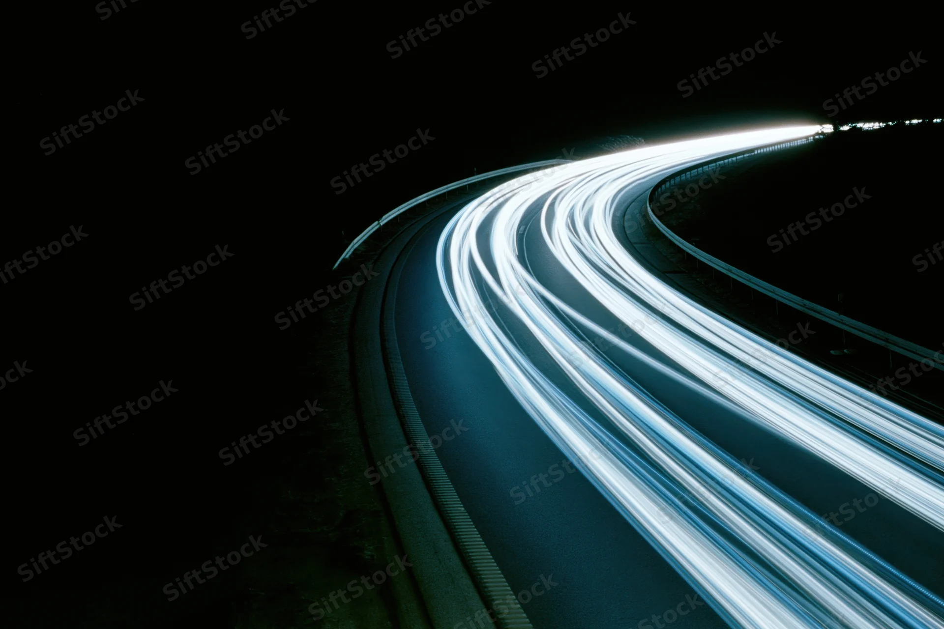 Curved highway at night with light trails from moving vehicles