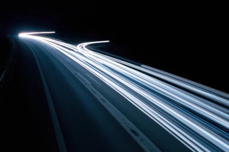 Curved highway at night with light trails from moving vehicles