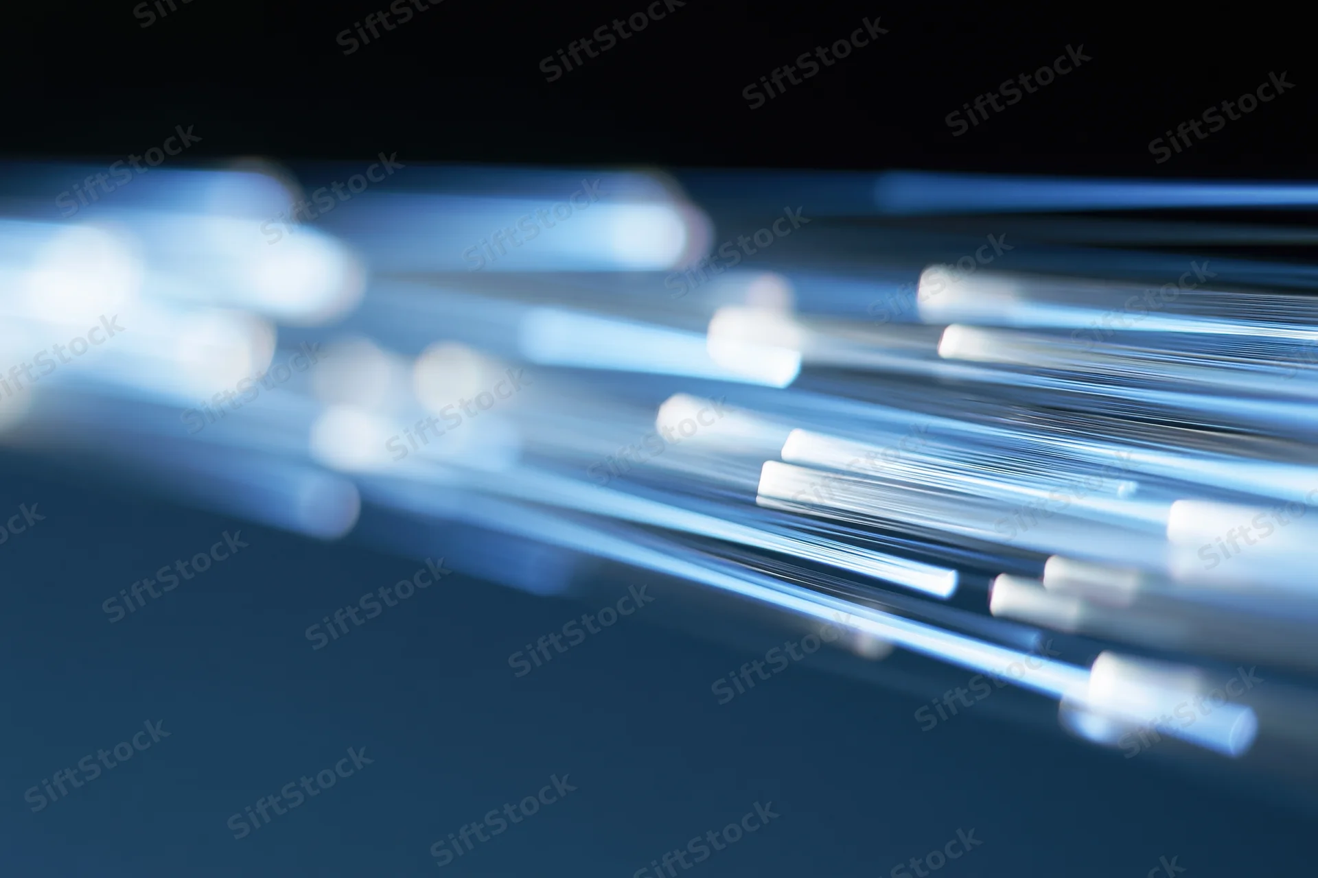 Fiber optic light trails streaking diagonally across a dark blue background in long exposure