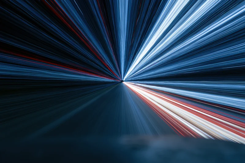 Motion-blurred light streaks radiating from a central point on a dark road at night