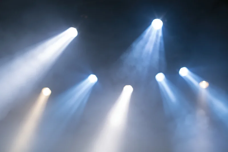 Multiple spotlights casting beams through haze in a dark stage environment