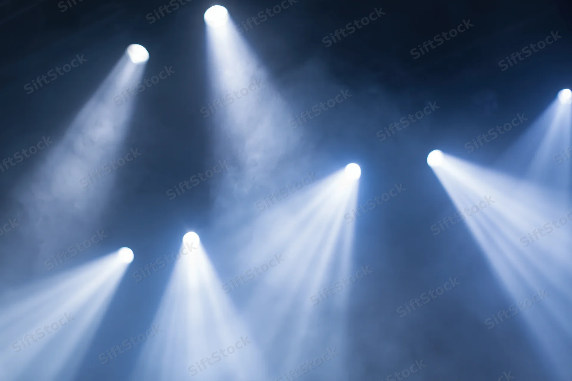Multiple spotlights casting beams through haze in a dark stage environment