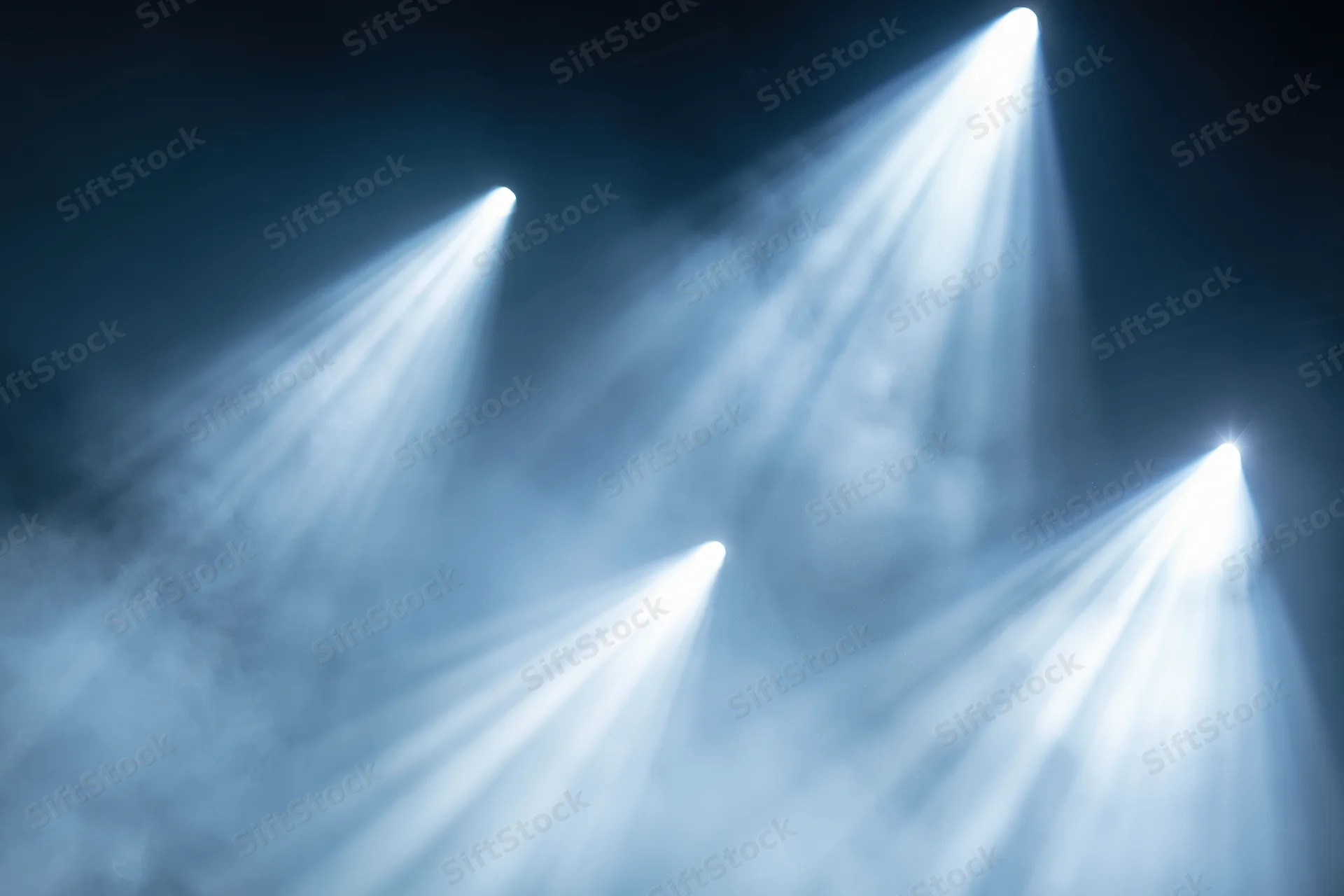 Multiple spotlights cutting through haze in a dark stage environment