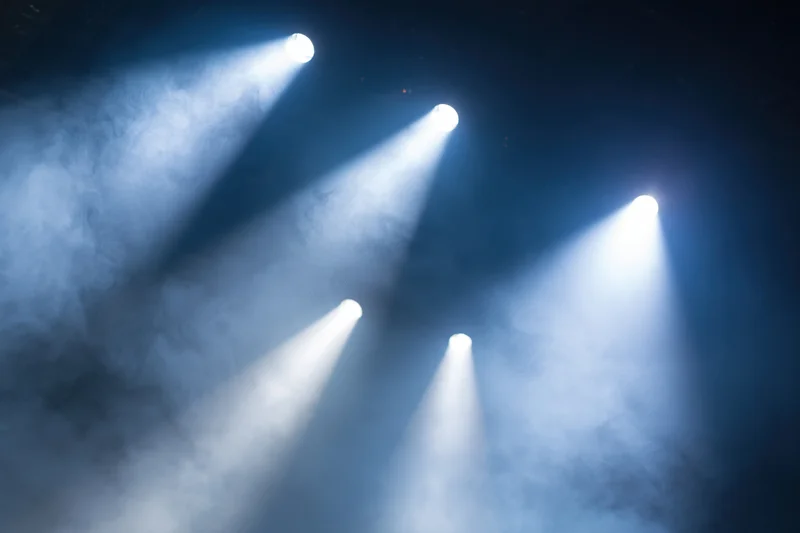 Multiple spotlights casting beams through haze in a dark stage environment