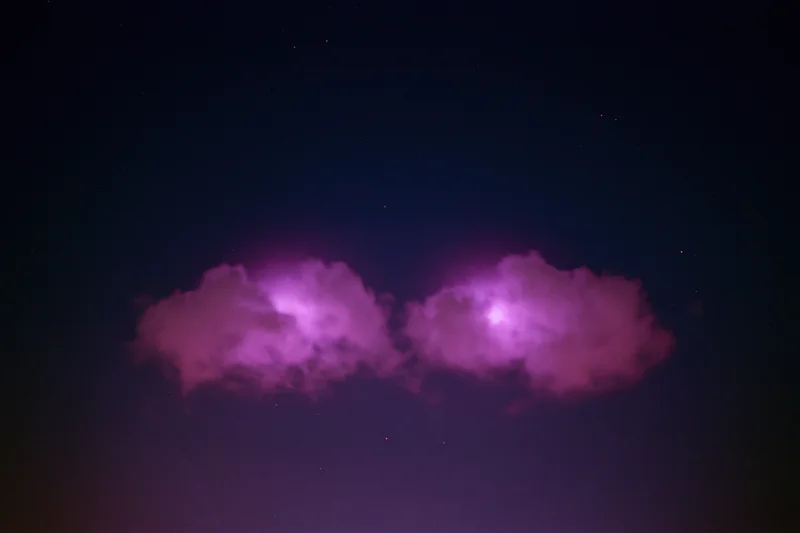 Two glowing magenta-pink cloud formations in the night sky