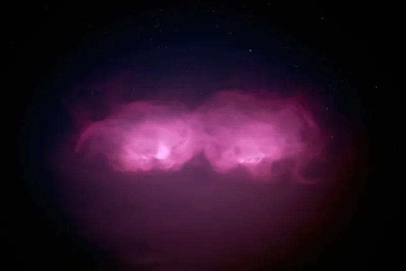 Two glowing magenta-pink cloud formations in the night sky