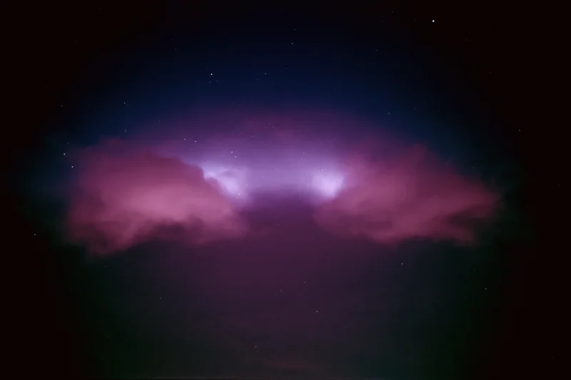 Glowing magenta-pink nebula clouds in dark night sky with scattered stars