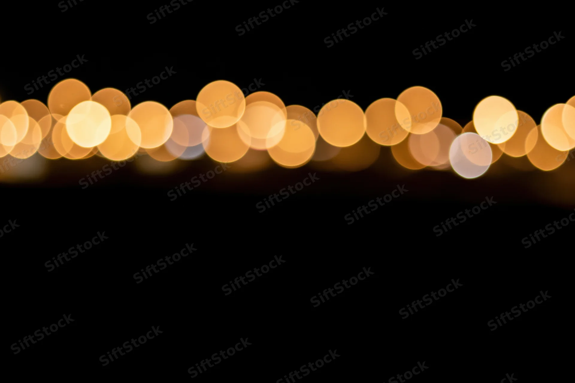 Golden bokeh circles arranged horizontally across the top of a dark frame with copyspace below