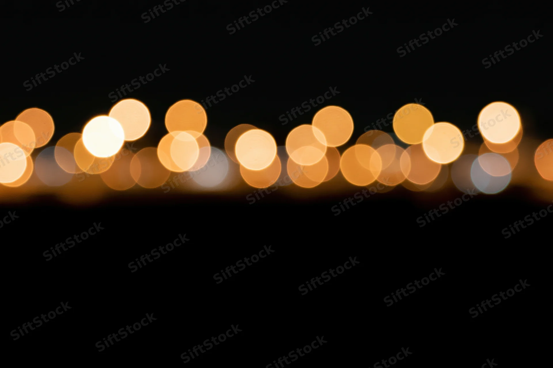 Golden bokeh circles scattered across the upper portion of a dark frame, creating a soft glowing background with copyspace below